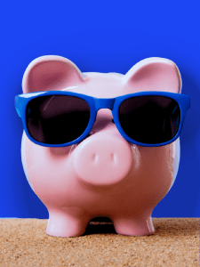 Cerdo alcancía rosa usando gafas de sol azules, frente a un fondo azul.